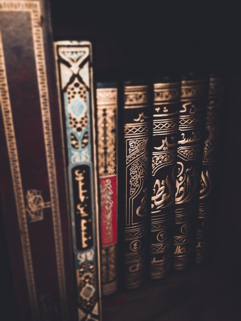 A close-up of ornate book spines with Arabic calligraphy on a dark bookshelf.